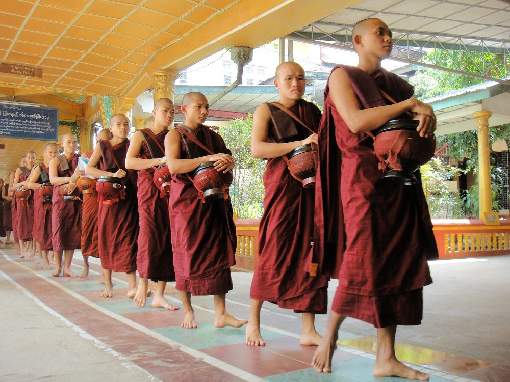 Tibetští mniši s tradiční mísou na ukládání jídla a věcí