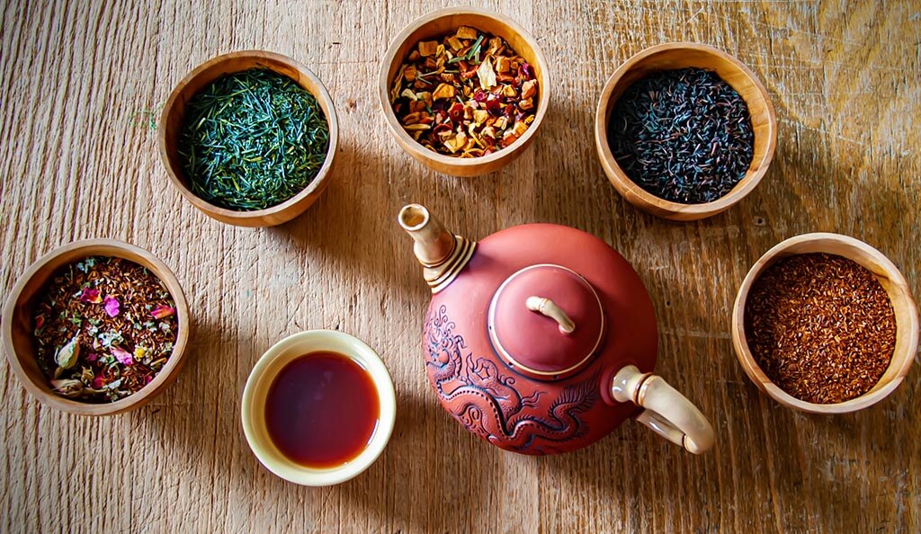Sypané čaje v šálcích a čajová konvička